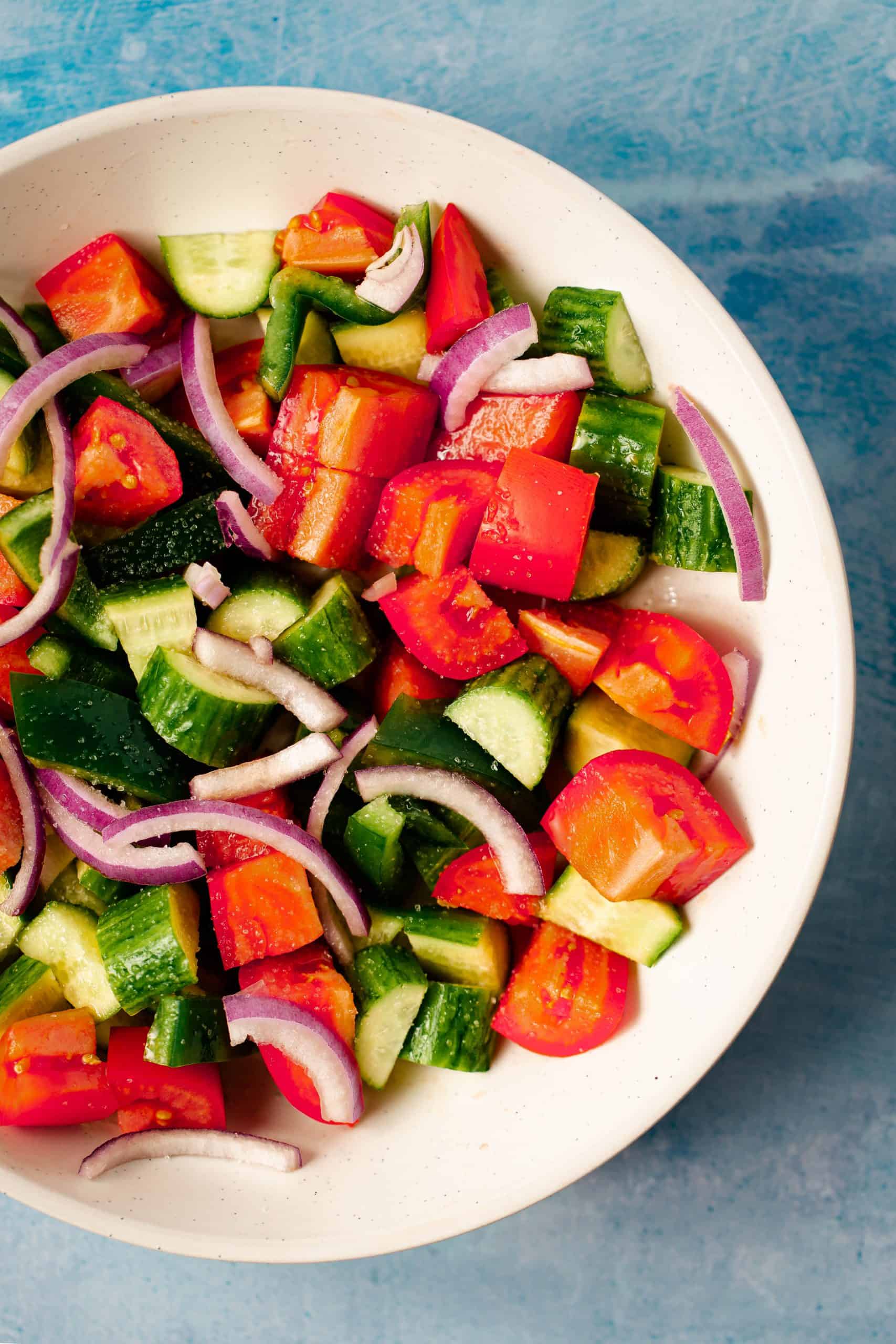 tomatoes, cucumber, and red onions chopped in a white bowl