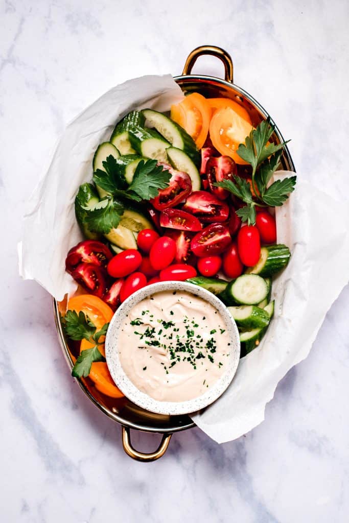 lebanese Tahini sauce with a platter full of tomatoes, cucumbers, and Parsley