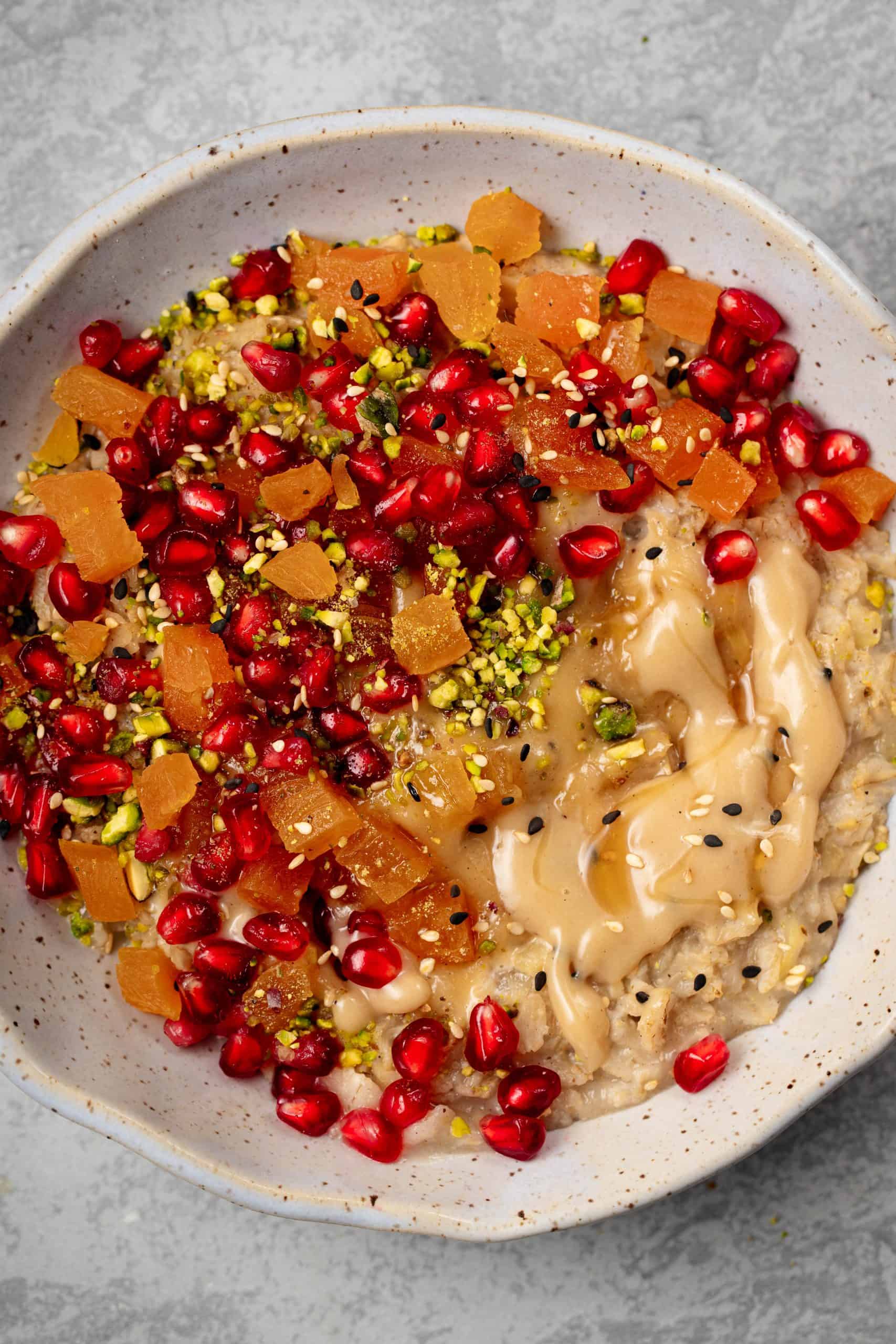 bowl of oats with pomergnates, apricots and tahini caramel
