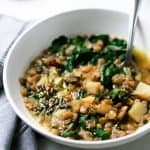 green lentils in a white bowl with steamed chard and spoon