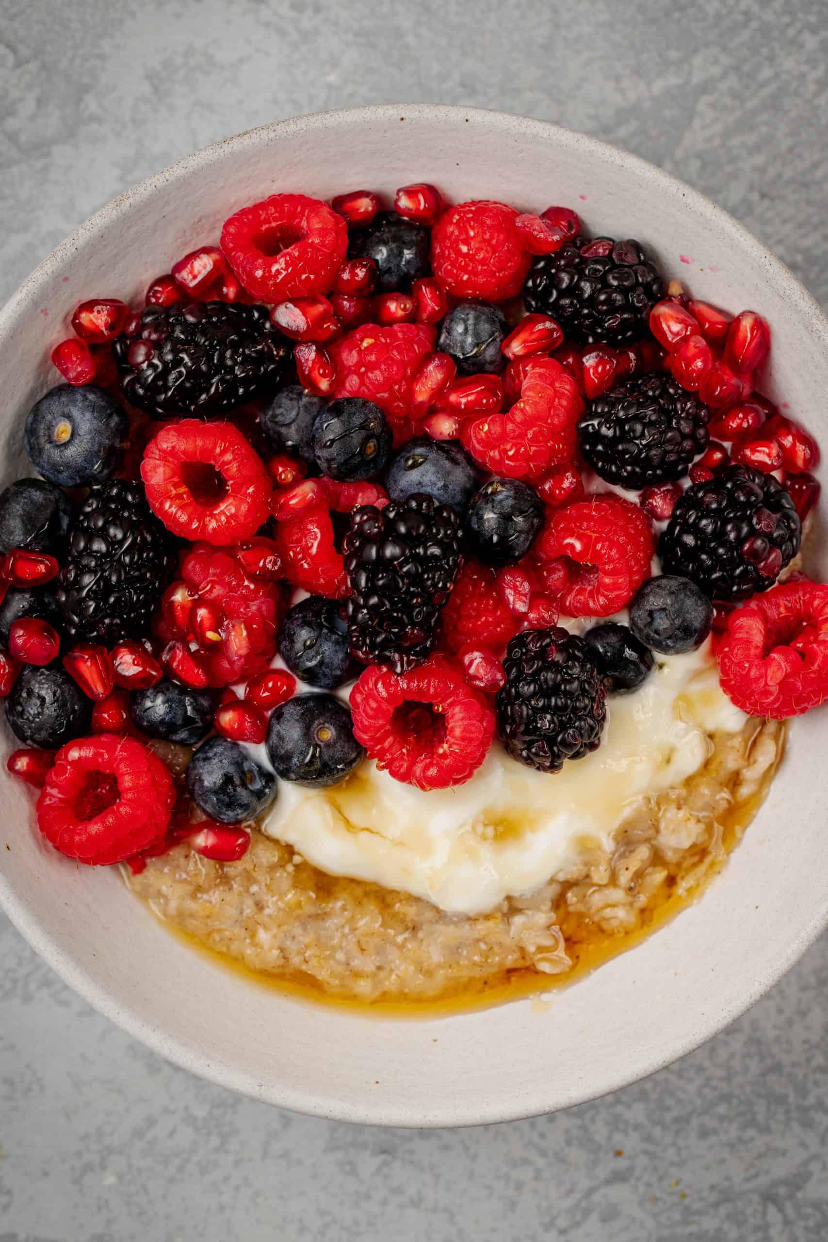A bowl of oatmeal with yogurt and lots of berries