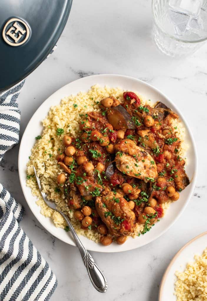 a plate of chicken and eggplant tagine on top of couscous