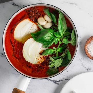 A white pot fill with san marzano tomato, onions, and basil