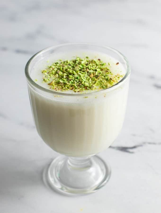 A glass filled with sahlab and topped with pistachio