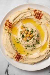 authentic hummus swirled on a plate with olive oil, chickpeas and paprika