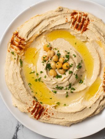 authentic hummus swirled on a plate with olive oil, chickpeas and paprika