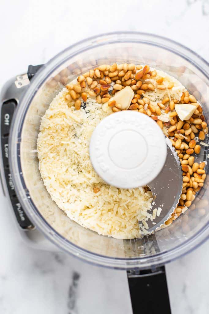 process photo of pine nuts, cheese and garlic in a food processor