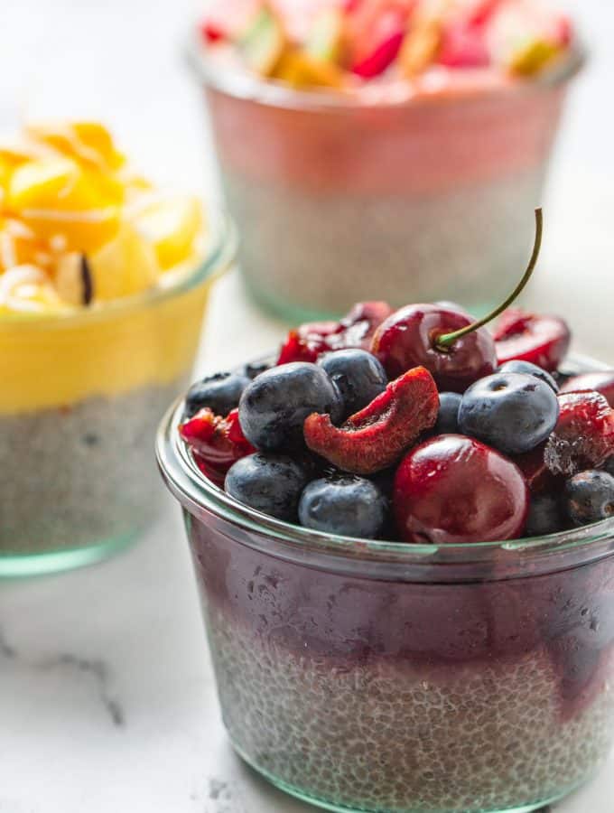 3 chia pudding in glass jar topped with pureed fruit and fresh fruit