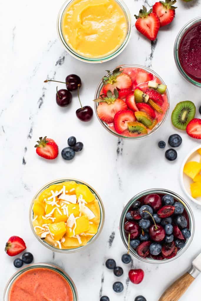 6 chia pudding parfaits in glasses jars some topped with fresh fruit others topped with fruit puree