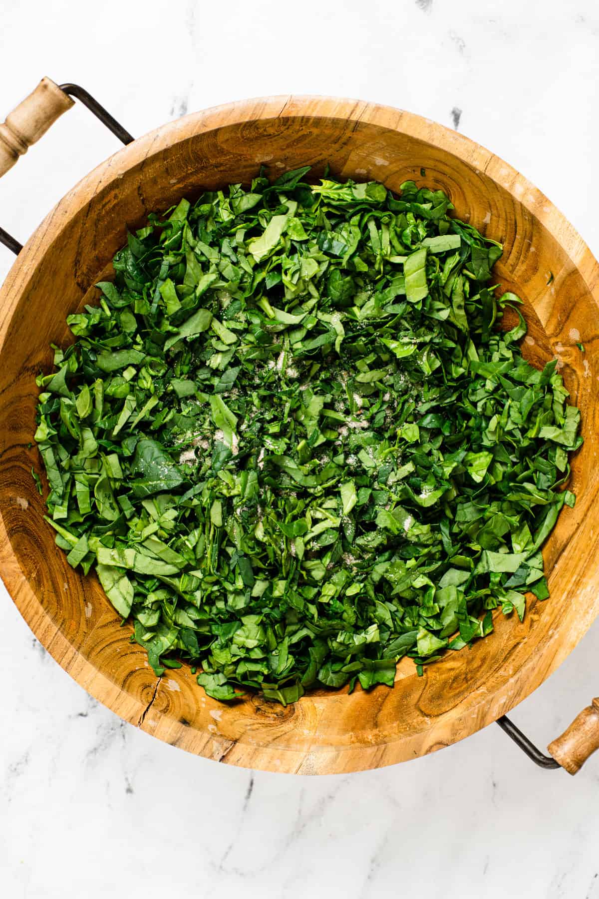 a wooden bowl with chopped fresh spinach