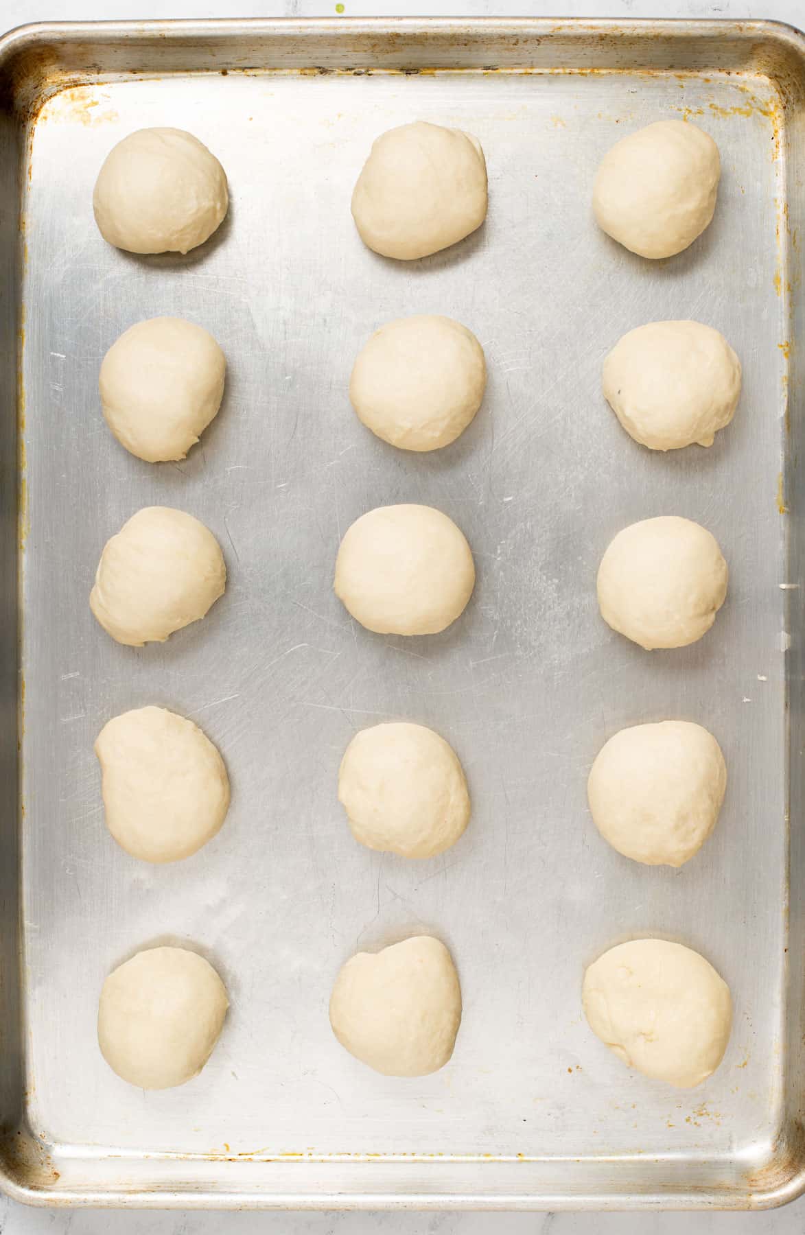 a baking sheet with weight rolled balls of fatayer dough